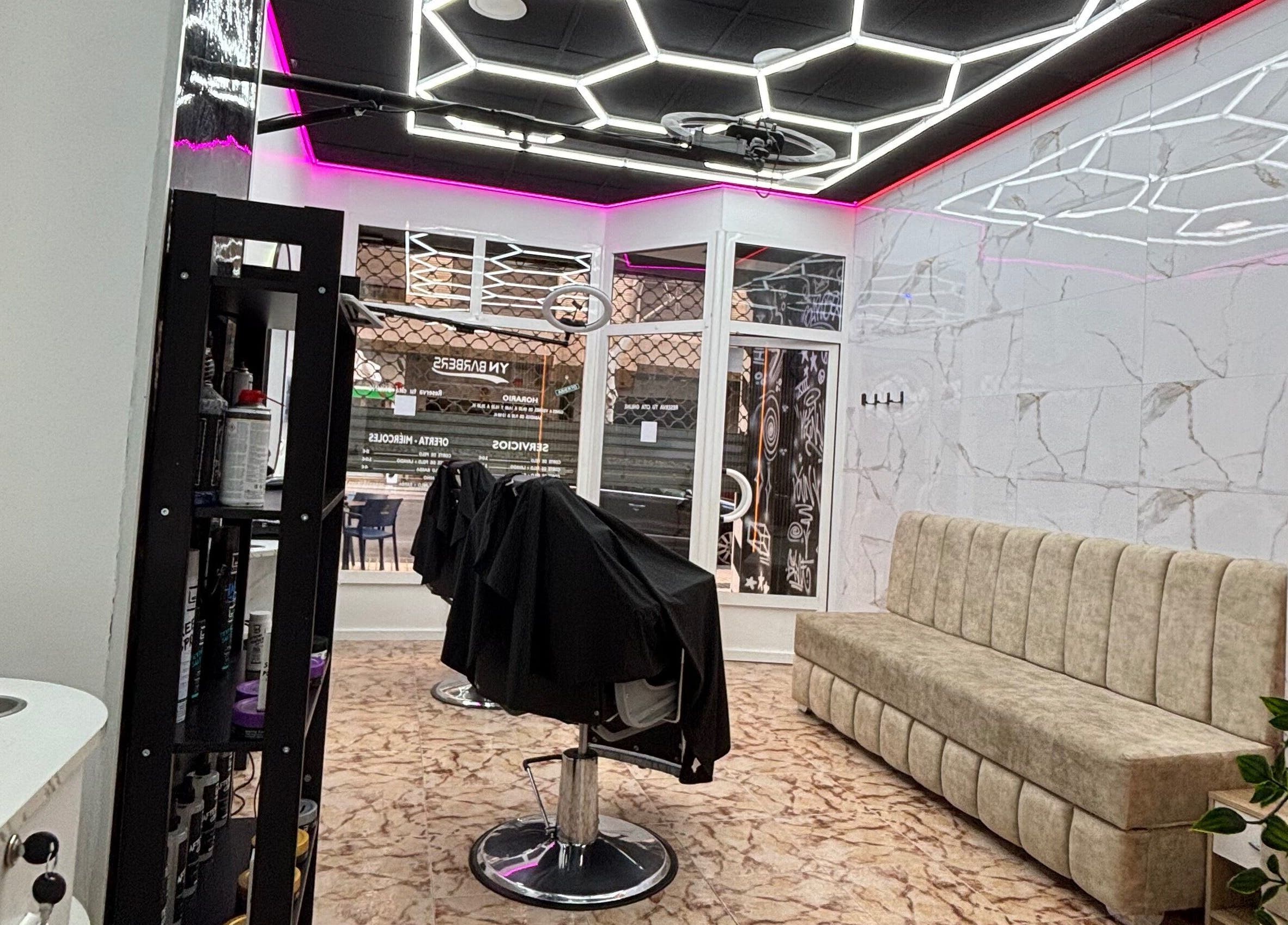 Interior de YN.Barber en Cartagena, Región De Murcia, ES, con diseño moderno y asientos cómodos bajo iluminación LED.