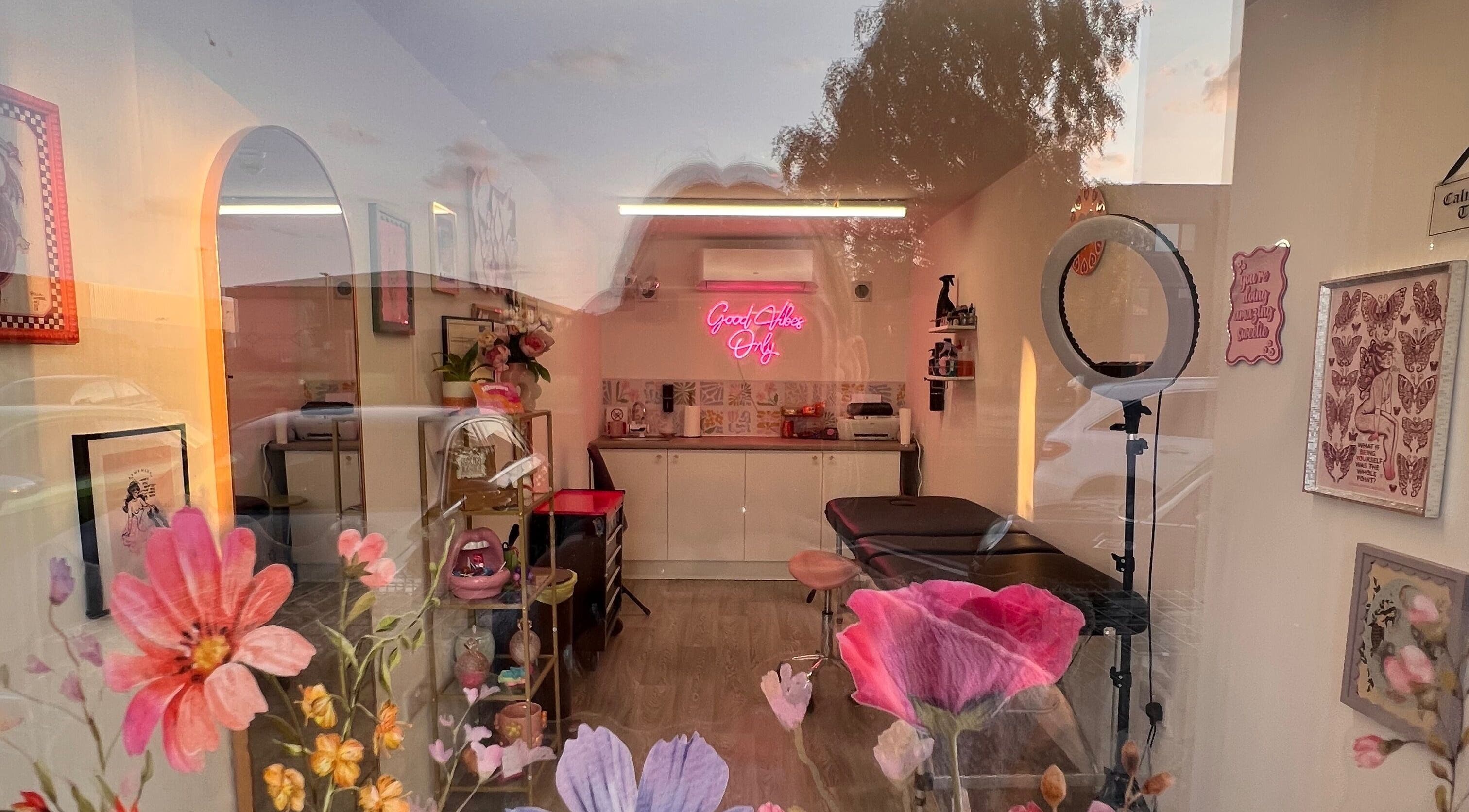 Chloe Duncan Tattoo studio interior with floral decor and neon sign in Rochester, England, GB.