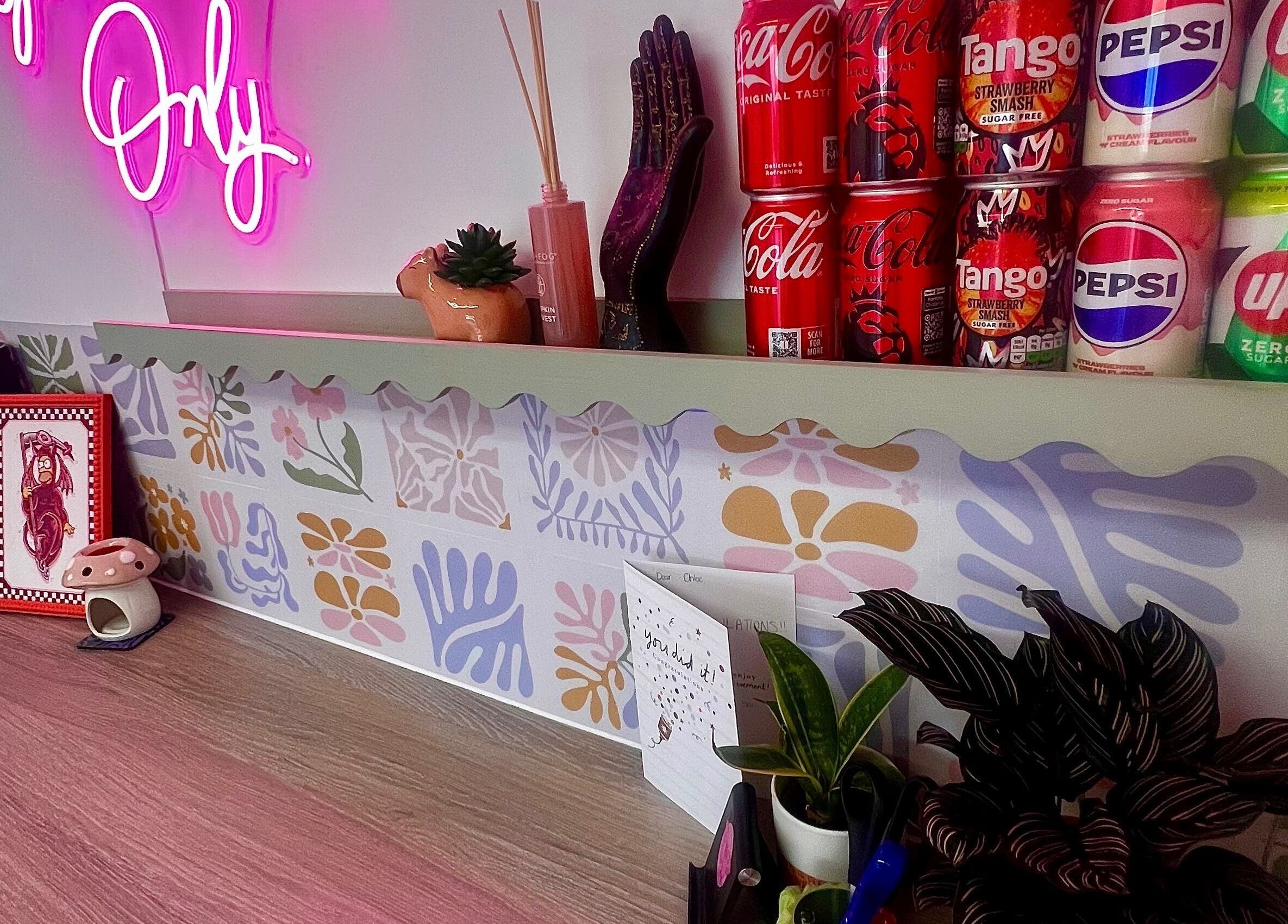 Vibrant counter at Chloe Duncan Tattoo, Rochester, England, with neon sign and decorative cans.