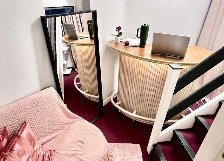 Interior aconchegante no Studio Zaina em Dublin, com sofá rosa e espelho elegante, refletindo o ambiente.