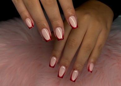 Red-tipped nails from Jennifer Audrey Nails & Beauty in Thurmaston, England, GB on a soft pink surface.