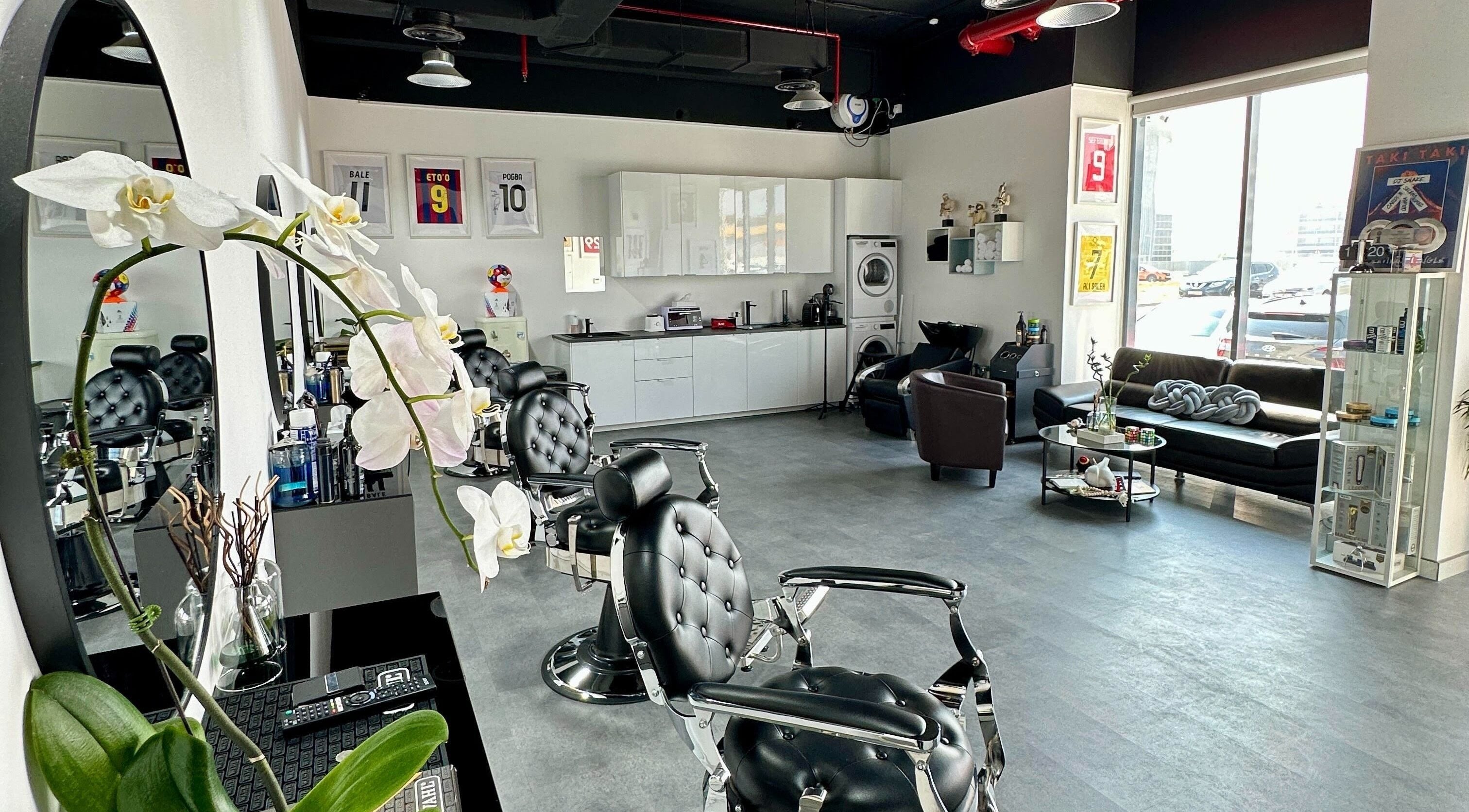 Trap Barbershop in Dubai, Dubai, AE featuring sleek barber chairs, orchids, and stylish decor.
