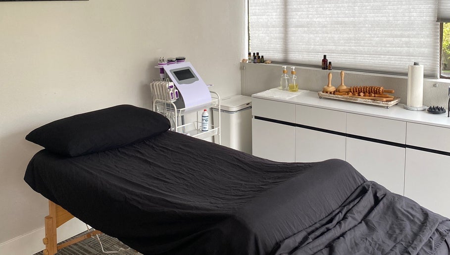 A serene treatment room at Divine Contours Studio, Citrus Heights, California, US with a massage table and essential oils.