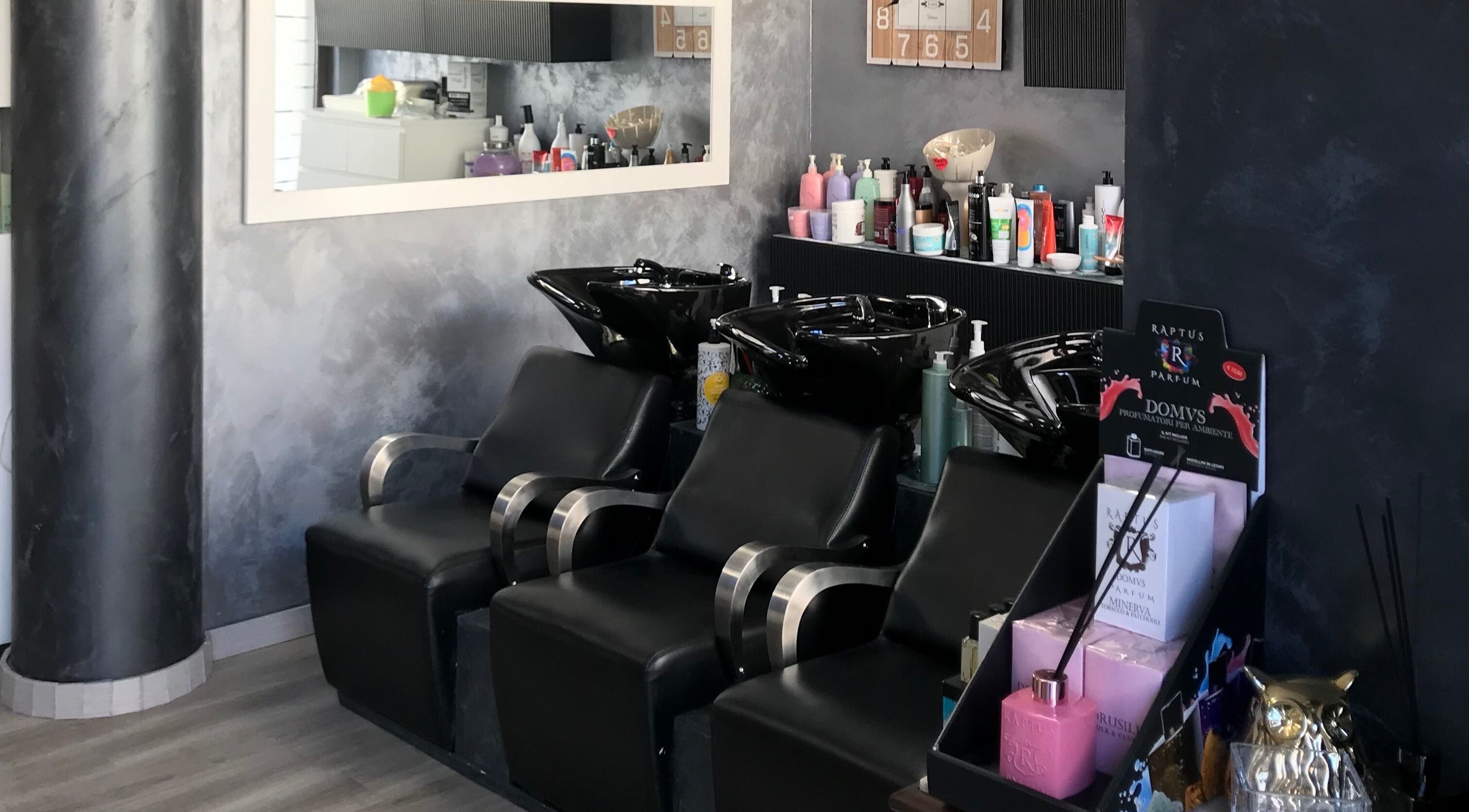 Zona lavaggio di Un Diavolo Per Capello a Brindisi, Puglia, IT con sedie nere e prodotti per capelli.