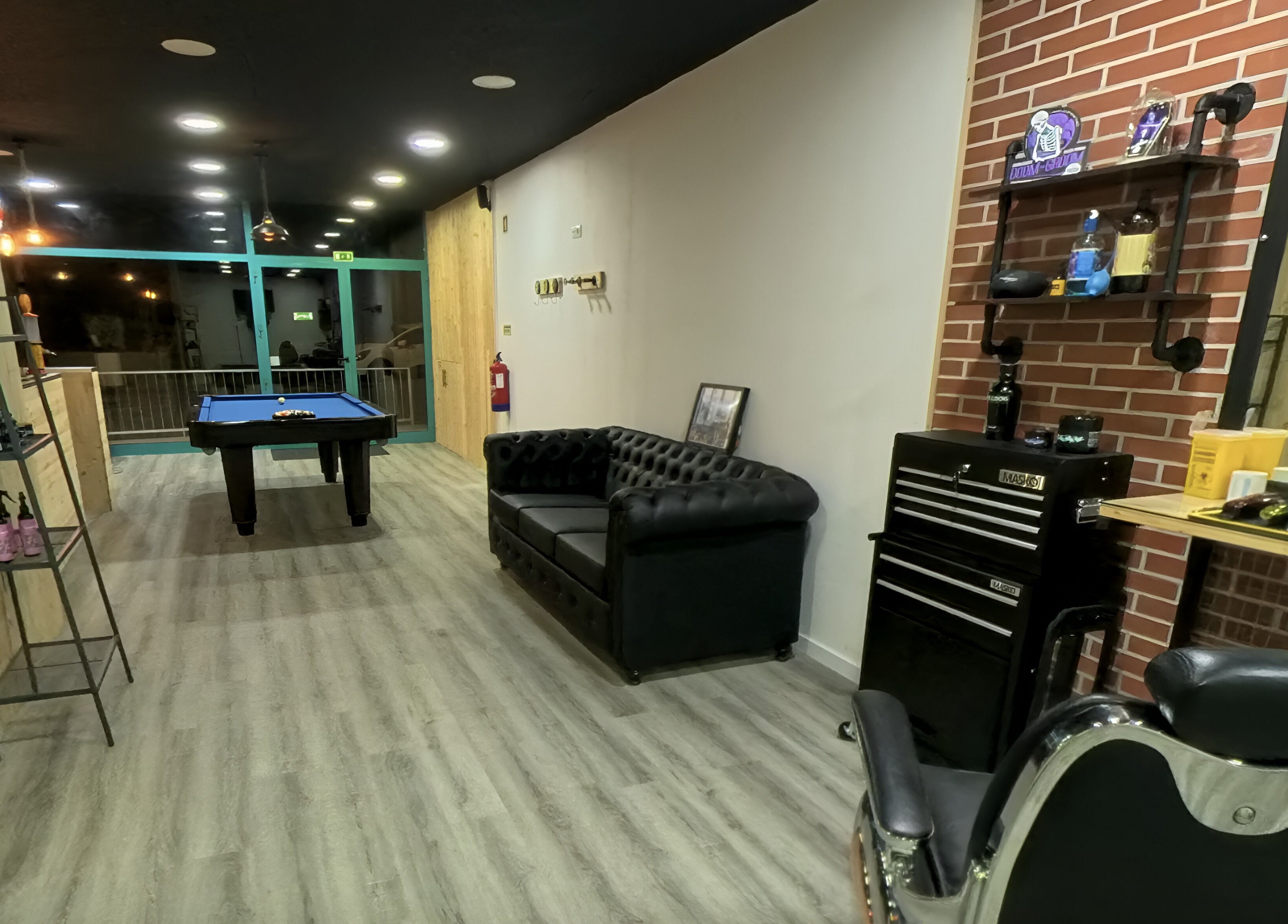 Ambiente acolhedor no Paddock Barbershop ®️, Lixa, Porto, PT, com sofá elegante e mesa de bilhar.