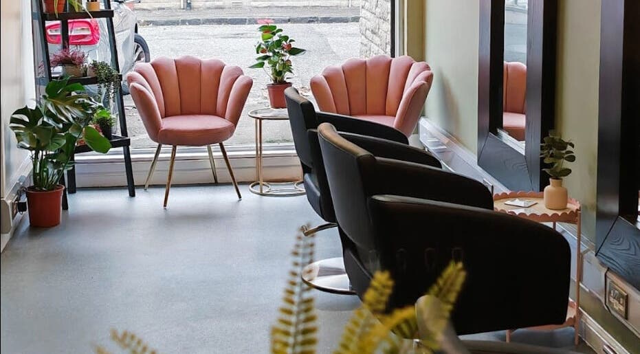 Stylish interior of Eden Hair Studio, Port Seton, Scotland, GB with pink chairs and lush plants.