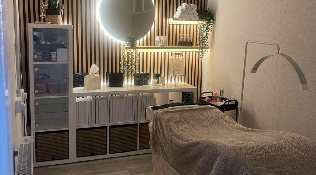 Cozy treatment room at Pāshoa, Pershore, England, GB, showcasing a modern setup with a glowing mirror.