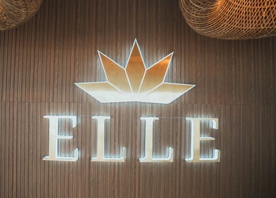 Illuminated sign of Elle. Massage Therapy & Wellness Iloilo City, PH on a textured wooden wall.