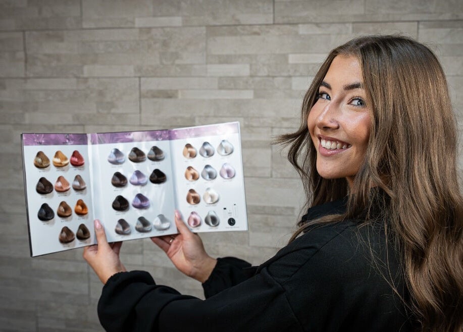 Stylist at AmberEliseHair in Ellon, Scotland, showcasing hair color options with a smile.