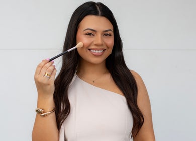 Smiling woman holding a makeup brush at By Paras, Carindale, Queensland, AU.