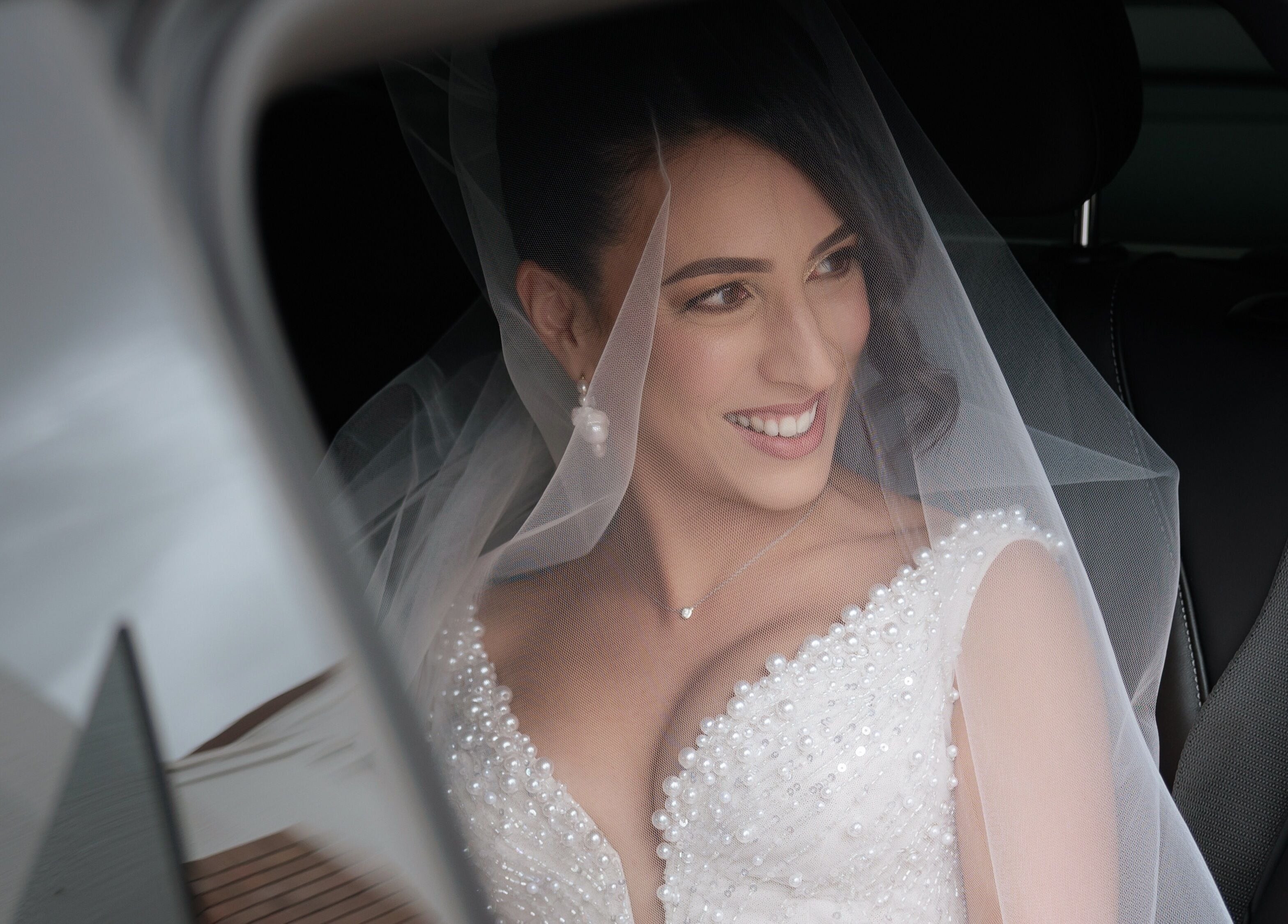 Smiling bride in car at By Paras, Carindale, Queensland, AU, in elegant gown and veil.