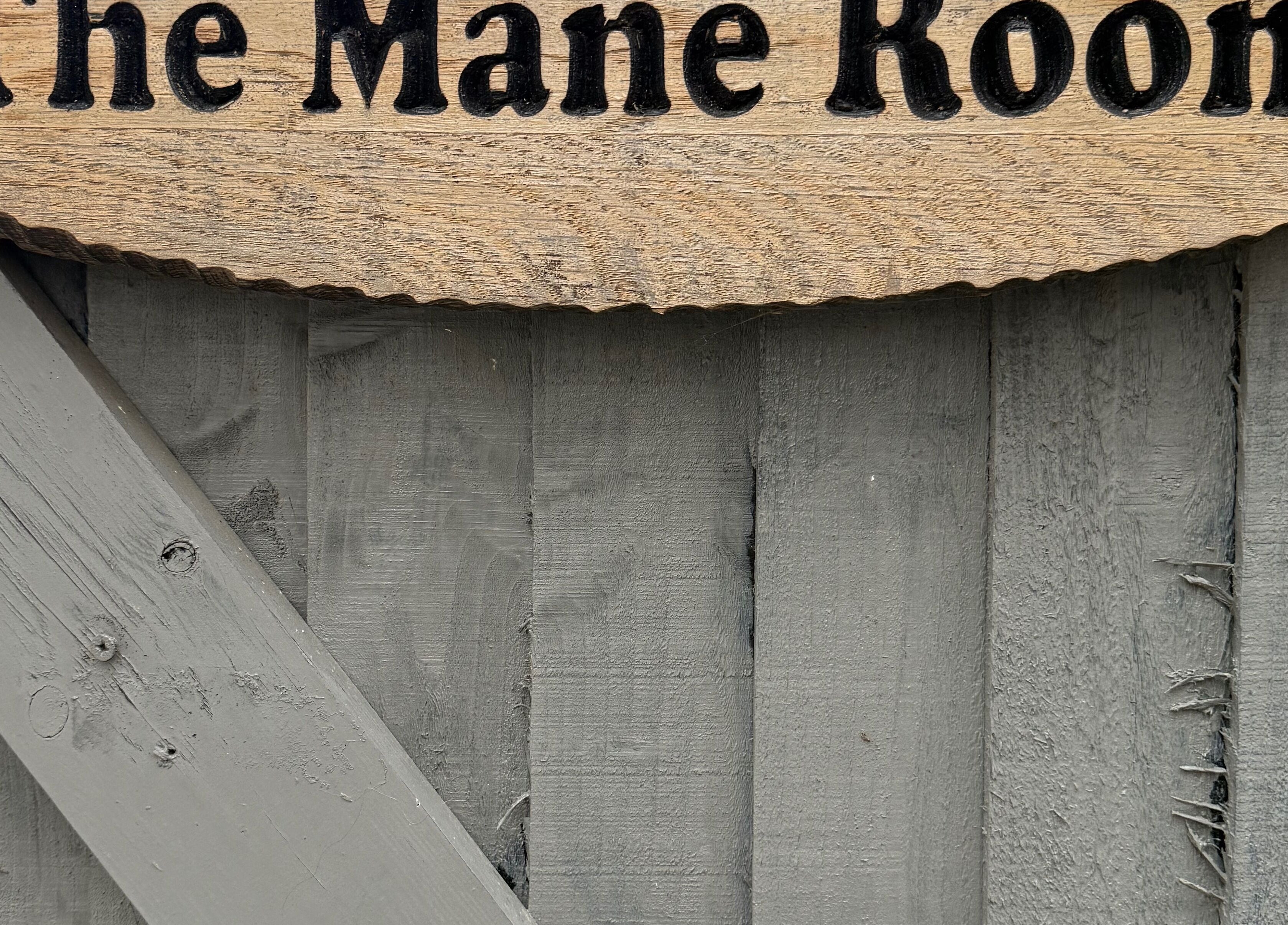 Wooden sign with 'The Mane Room' at Cookham, England, GB on rustic background.