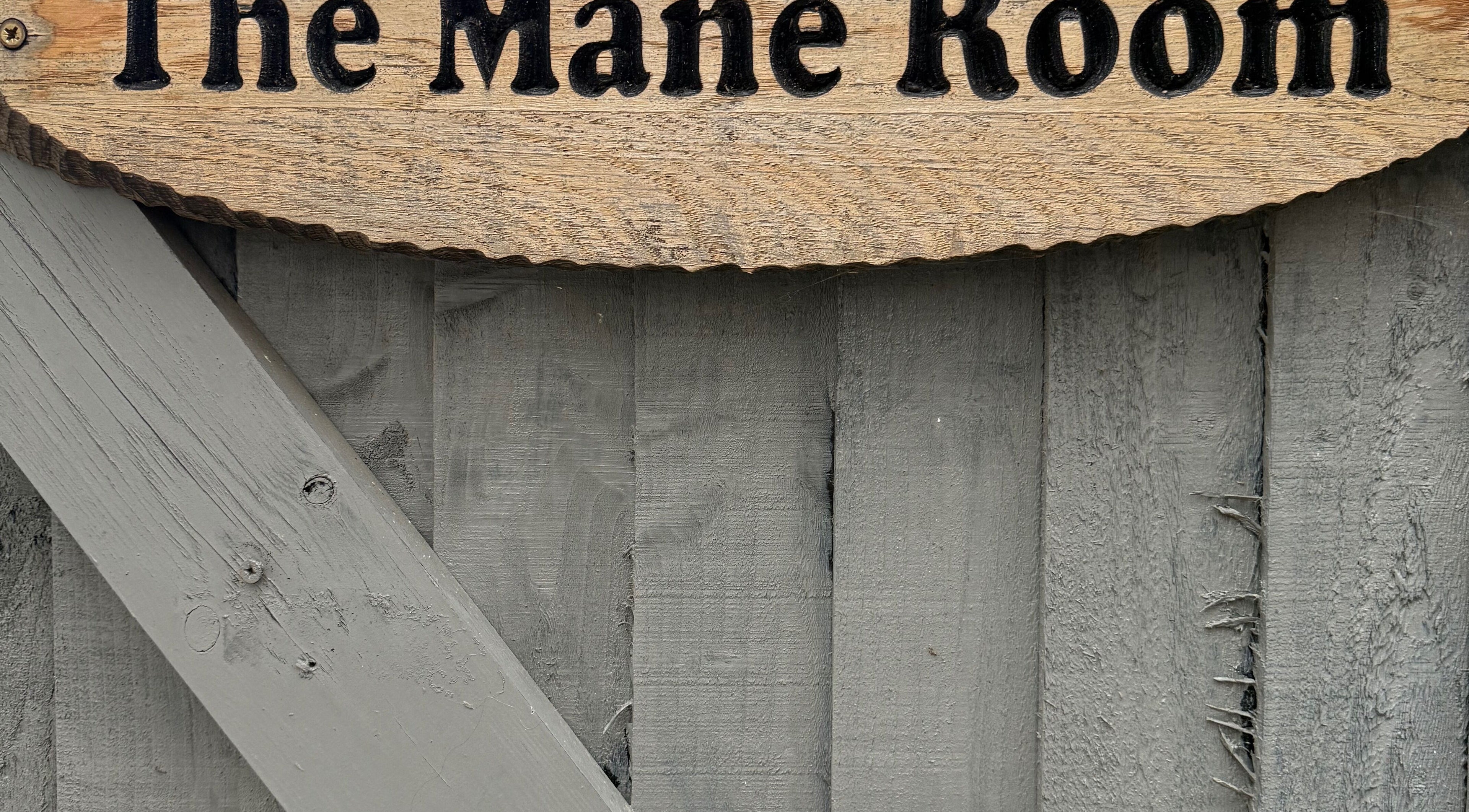 Wooden sign with 'The Mane Room' at Cookham, England, GB on rustic background.