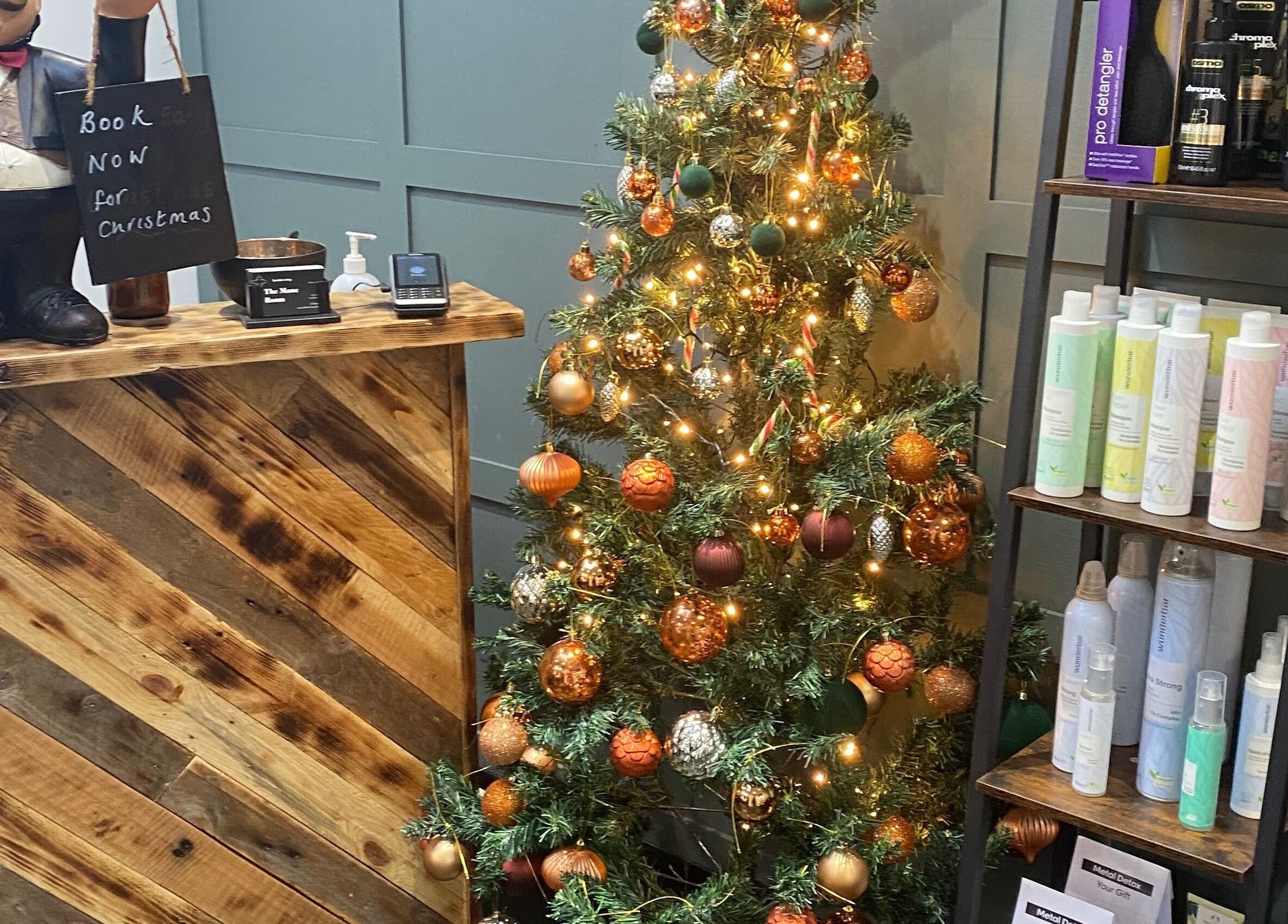 Reception desk with Christmas decor at The Mane Room in Cookham, England, GB, adorned with products and a festive tree.