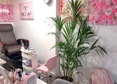 Naiyah Nails salon in London, England, GB features a stylish nail care setup with pink floral decor and comfy seating.