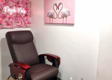 Comfortable chair at Naiyah Nails, London, England, GB, adorned with a pink floral wall art decor.