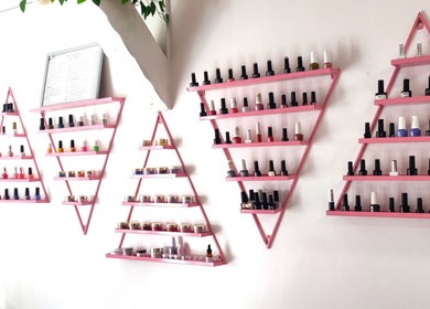 Colorful nail polish display on pink shelves at Naiyah Nails, London, England, GB.