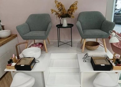 Interior moderno de Trendy y Nails Poble Sec en Barcelona, Catalunya, ES, con elegantes sillones grises y equipos de manicura.