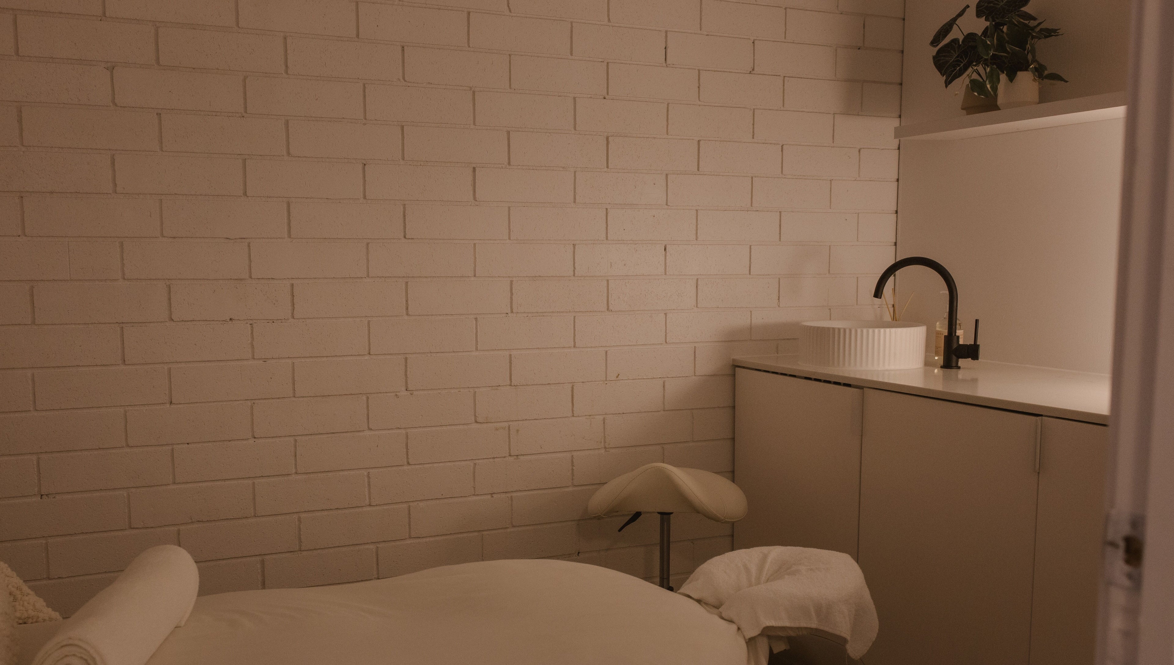 Calm massage room at Ettalong Massage, Ettalong Beach, New South Wales, AU featuring a cozy bed and modern sink.