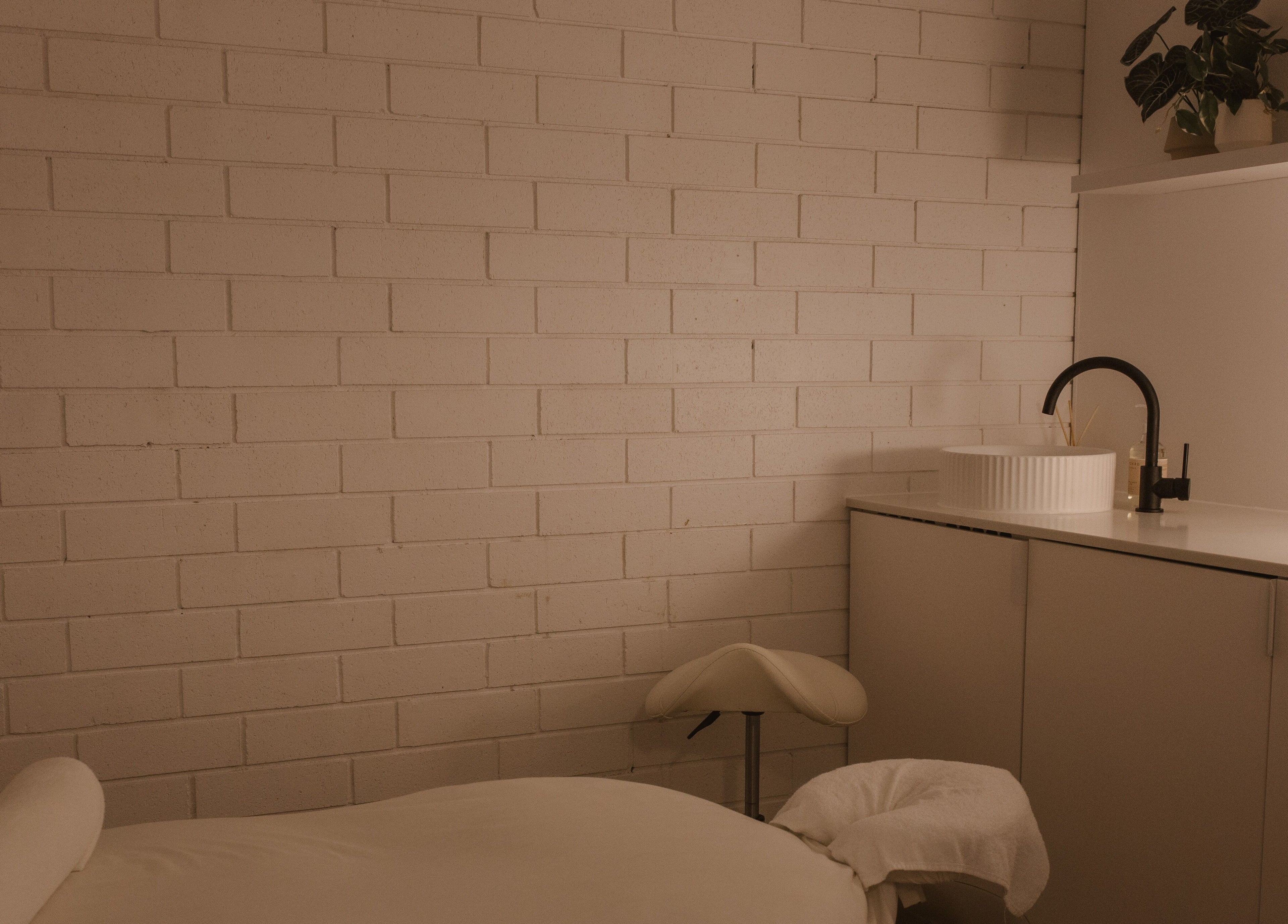 Calm massage room at Ettalong Massage, Ettalong Beach, New South Wales, AU featuring a cozy bed and modern sink.