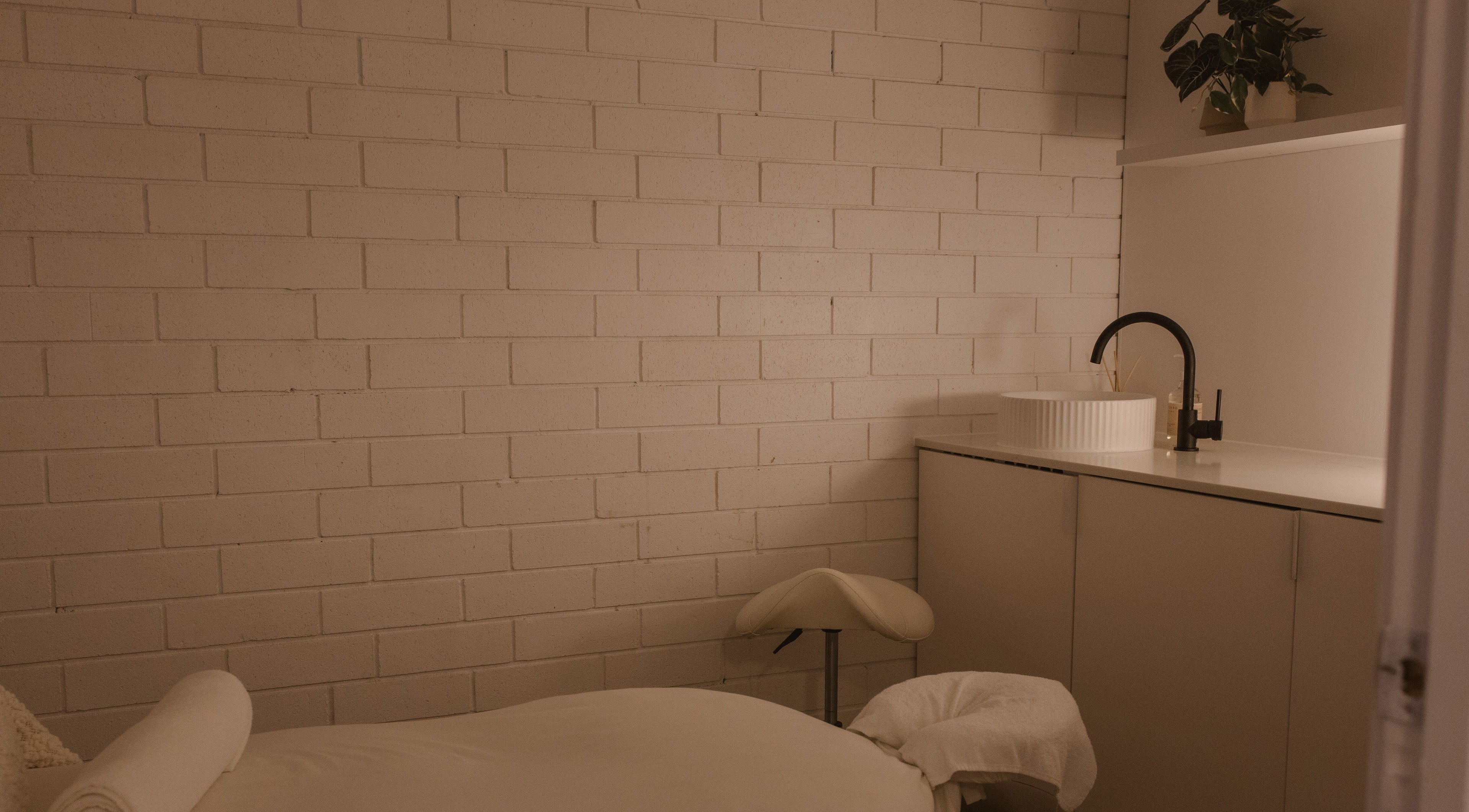 Calm massage room at Ettalong Massage, Ettalong Beach, New South Wales, AU featuring a cozy bed and modern sink.