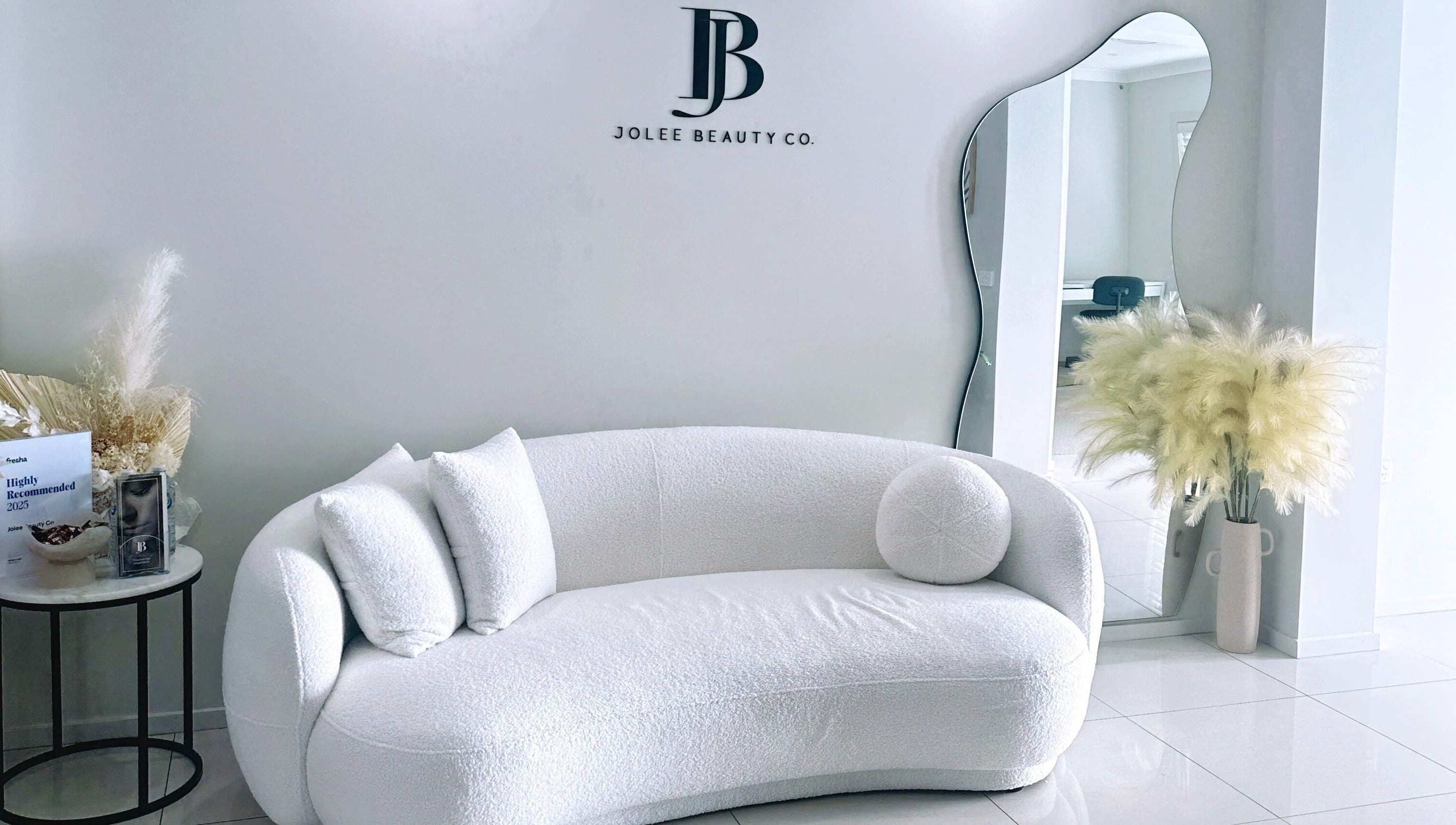 Luxury lounge area at Jolee Beauty Co - Prestons, Prestons, New South Wales, AU with stylish decor and mirror.