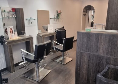 Interior moderno de AXICIAhair PERRUQUERIA en Barcelona, Catalunya, ES, con sillas y espejos elegantes.