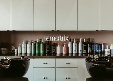 Xelia Hair & MediSpa inc, Moncton, NB: Array of haircare products on shelves above salon wash basin.