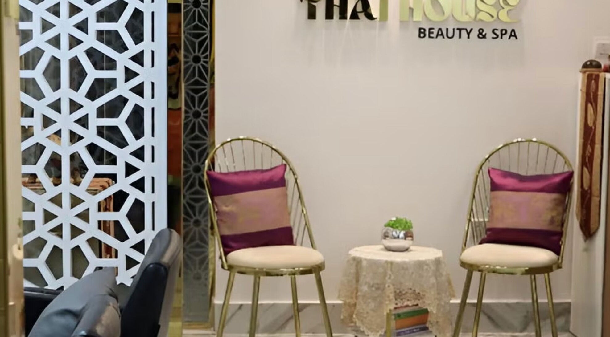 Stylish seating area at Home Service - Thai House Beauty and Spa in AE showcasing golden chairs and decor.