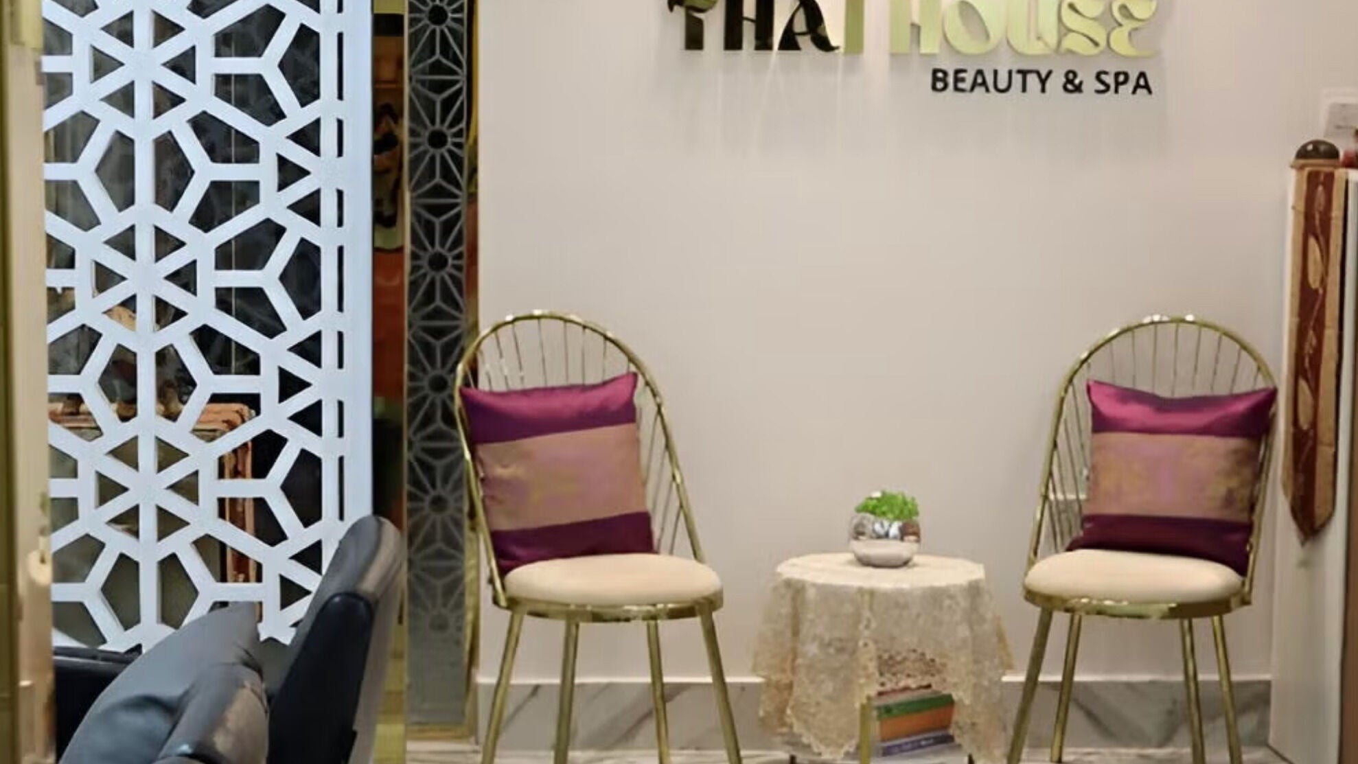 Stylish seating area at Home Service - Thai House Beauty and Spa in AE showcasing golden chairs and decor.