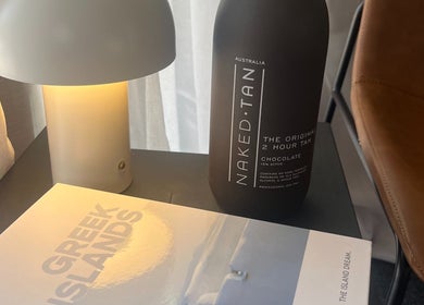 Cozy nook with a lamp, Naked Tan bottle, and book at Glow With Me Alexia, Melbourne, Victoria, AU.