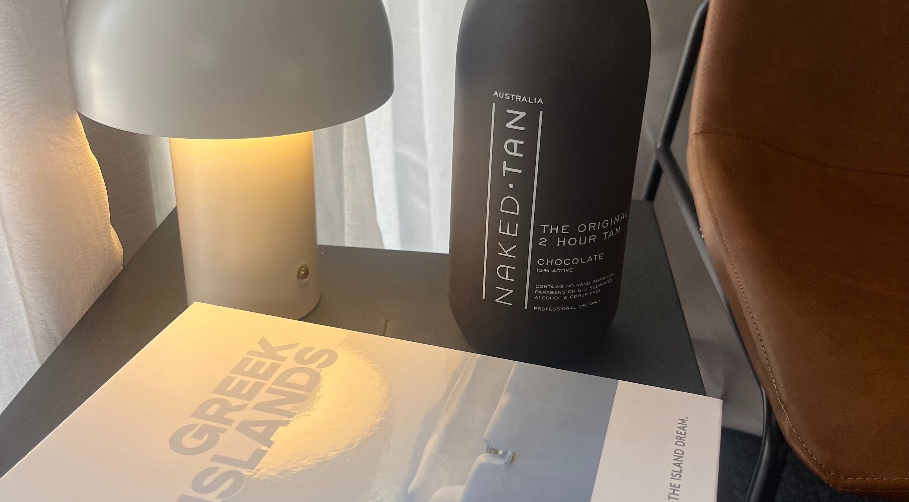 Cozy nook with a lamp, Naked Tan bottle, and book at Glow With Me Alexia, Melbourne, Victoria, AU.