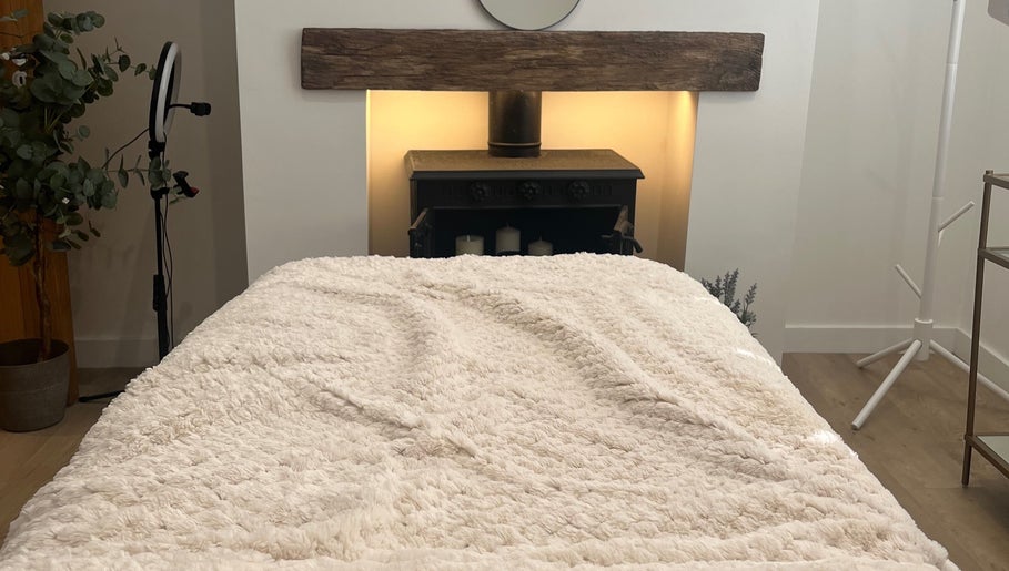 Cozy treatment room at The Glow Collective, Lichfield, England, GB, featuring a plush bed and calming decor.