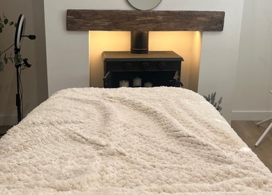 Cozy treatment room at The Glow Collective, Lichfield, England, GB, featuring a plush bed and calming decor.