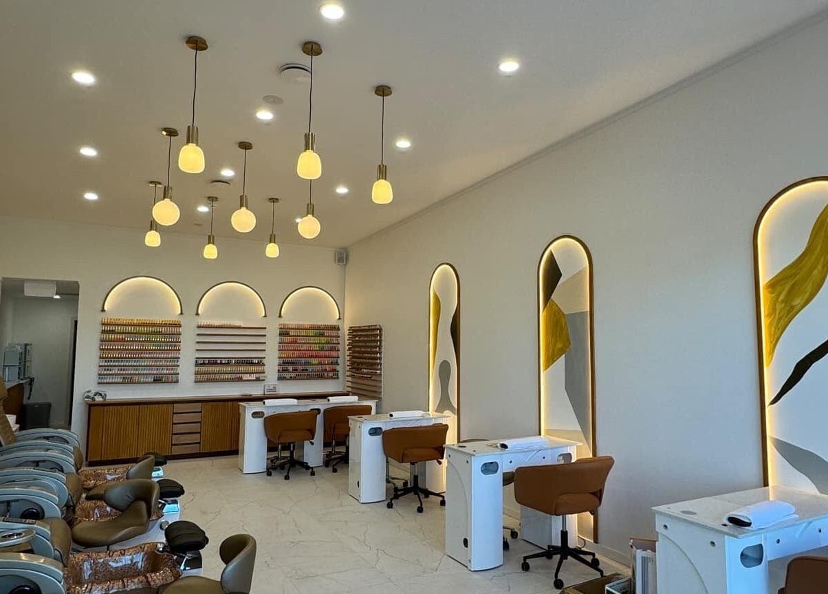 Interior of Sunshine Nails & Beauty in Auckland, NZ, showcasing chic nail stations and plush seating.