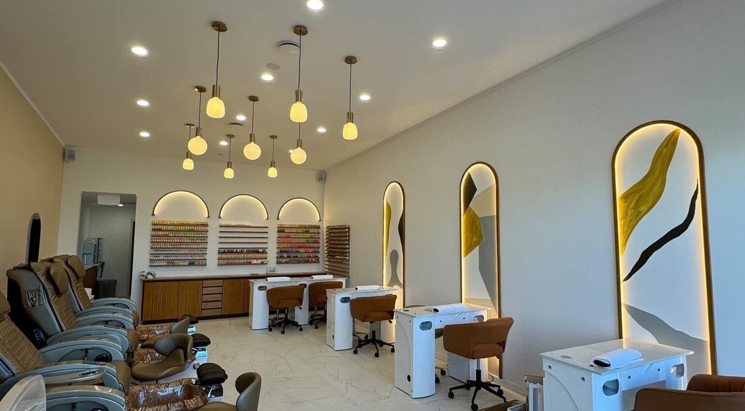 Interior of Sunshine Nails & Beauty in Auckland, NZ, showcasing chic nail stations and plush seating.