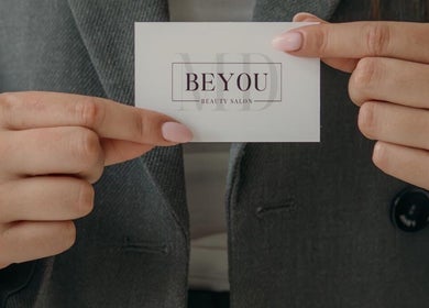 Visitekaartje van Be You Beautysalon Gorinchem, Zuid-holland, NL, vastgehouden door vrouw met roze nagels.