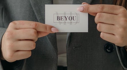 Visitekaartje van Be You Beautysalon Gorinchem, Zuid-holland, NL, vastgehouden door vrouw met roze nagels.
