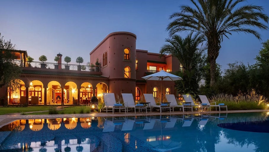 Poolside view at Star Seed + Violet Stopford Retreat Popup, London, England, GB, with palm trees and evening lights.