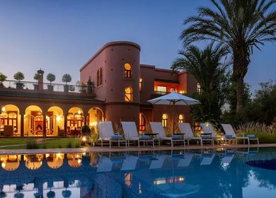 Poolside view at Star Seed + Violet Stopford Retreat Popup, London, England, GB, with palm trees and evening lights.
