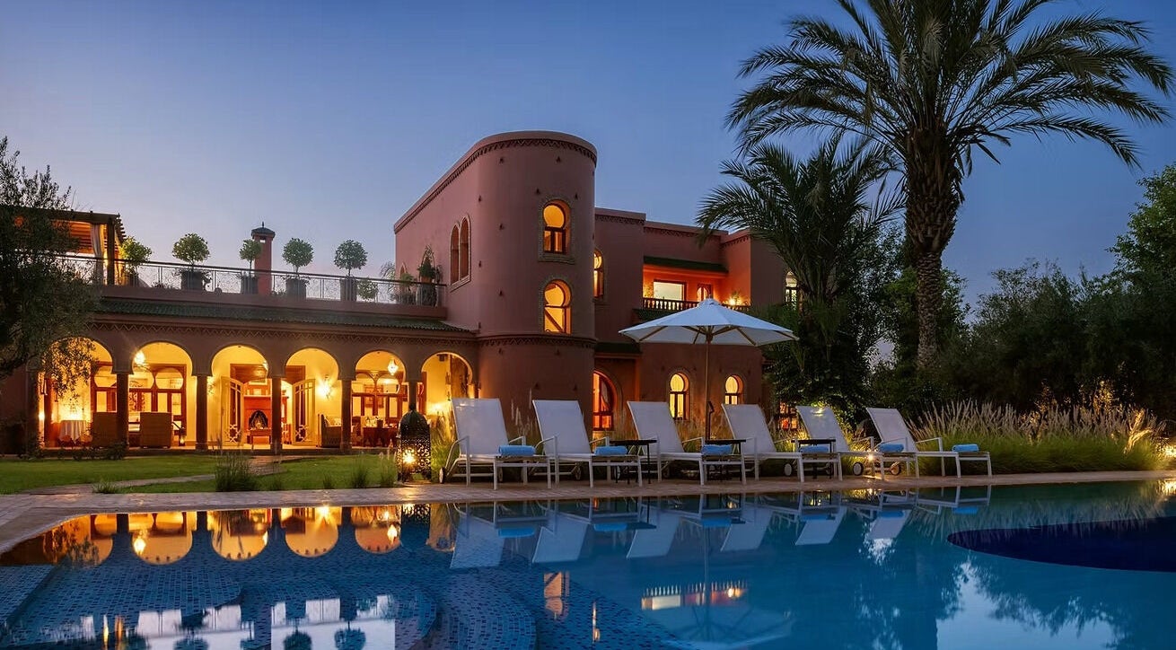 Poolside view at Star Seed + Violet Stopford Retreat Popup, London, England, GB, with palm trees and evening lights.
