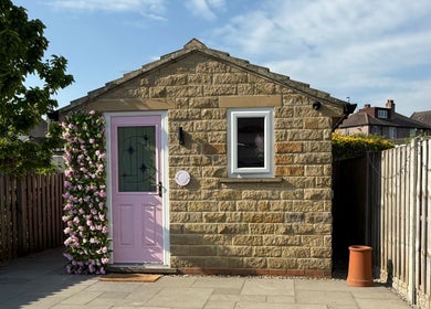 Charming facade of The Pink Beauty Room in Huddersfield, England, featuring pink door and floral decor.