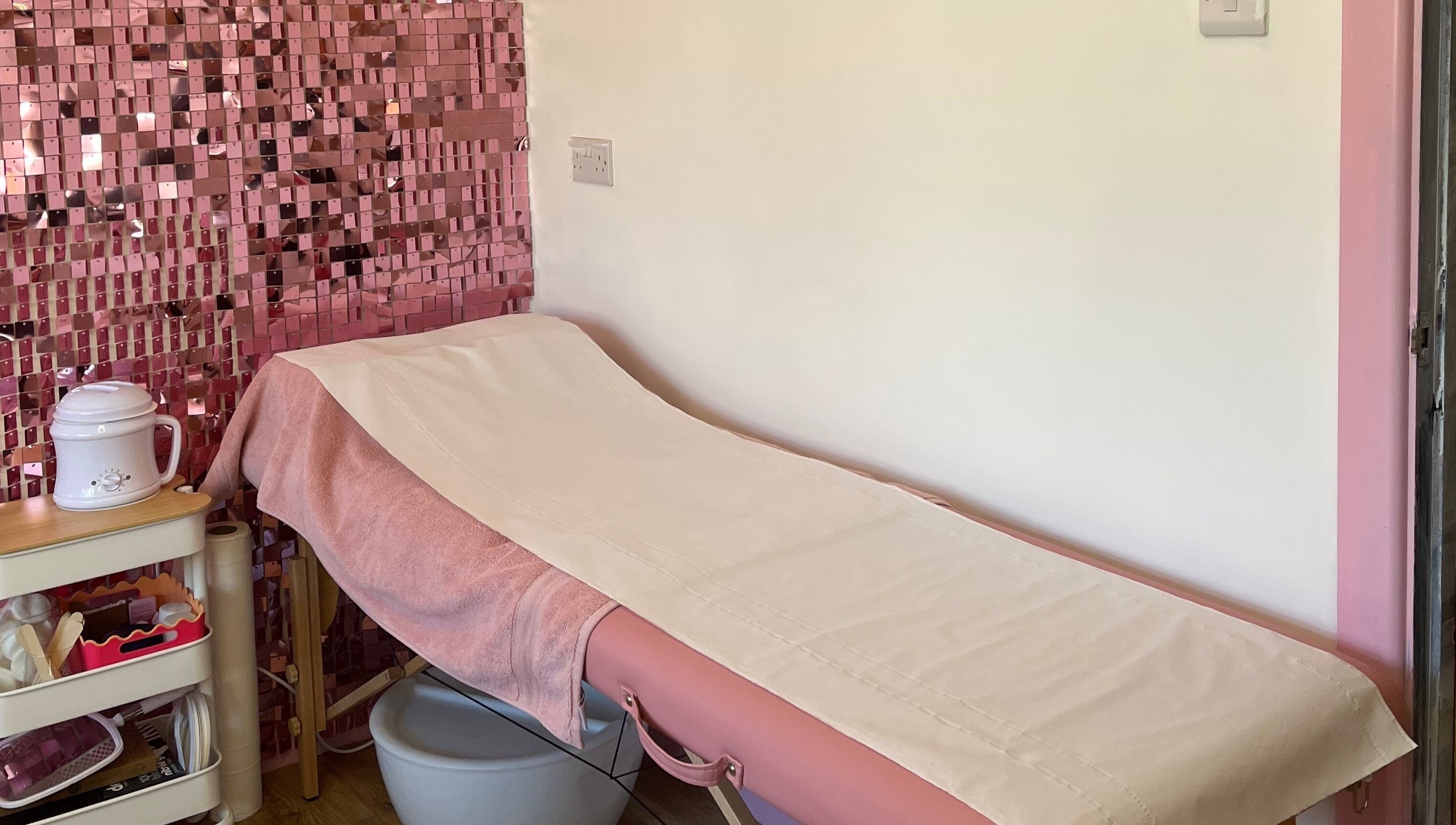 Cozy treatment room at Sugar Tips, Fareham, England, GB with pink bed and decor for relaxing beauty sessions.