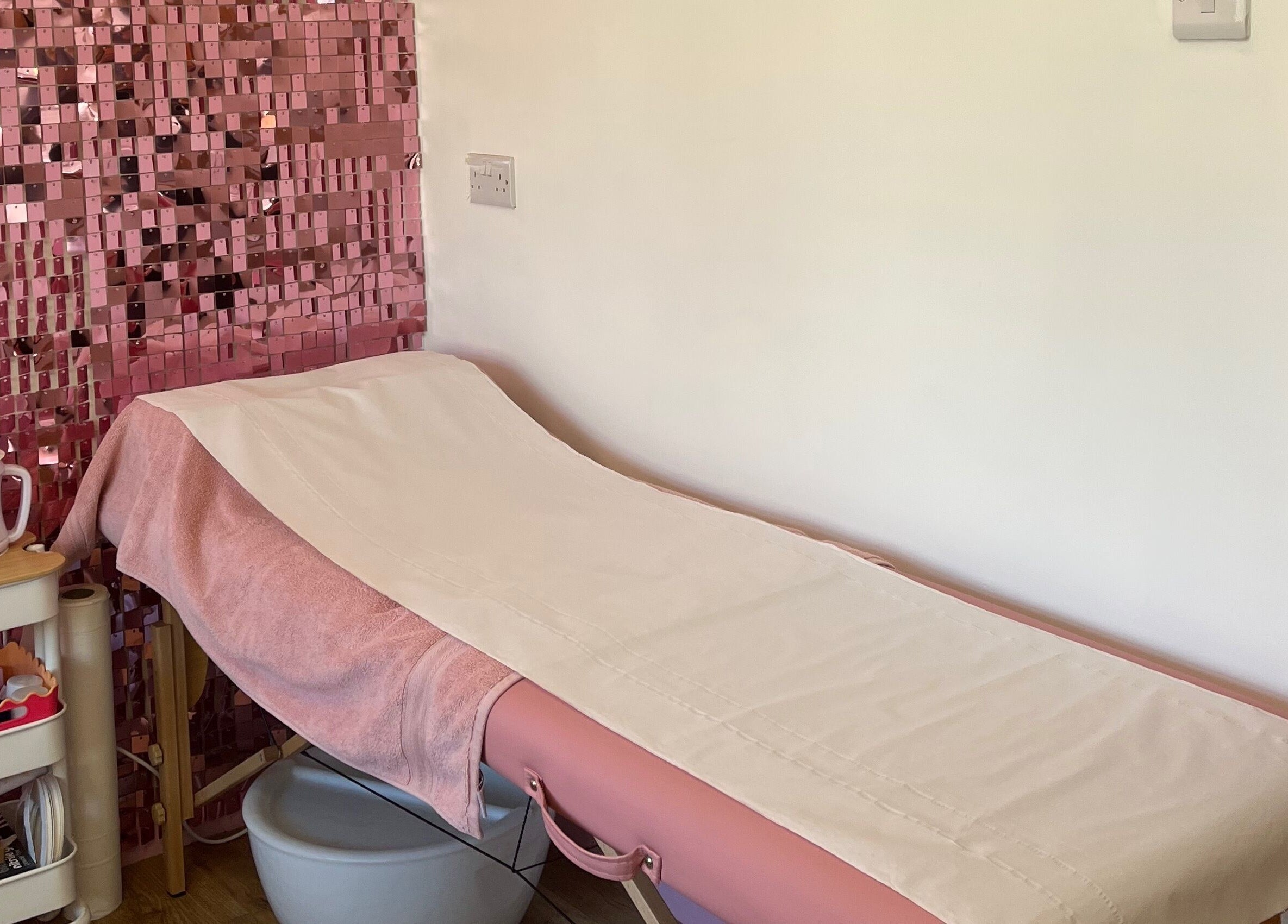 Cozy treatment room at Sugar Tips, Fareham, England, GB with pink bed and decor for relaxing beauty sessions.