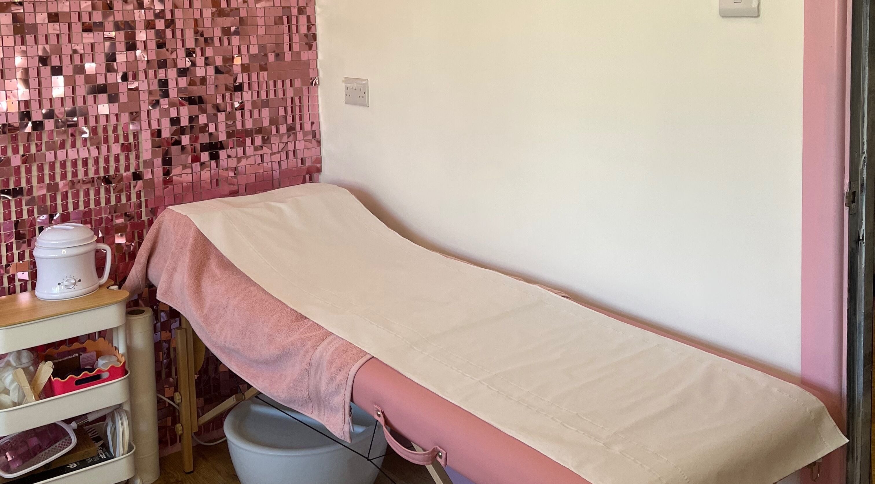 Cozy treatment room at Sugar Tips, Fareham, England, GB with pink bed and decor for relaxing beauty sessions.