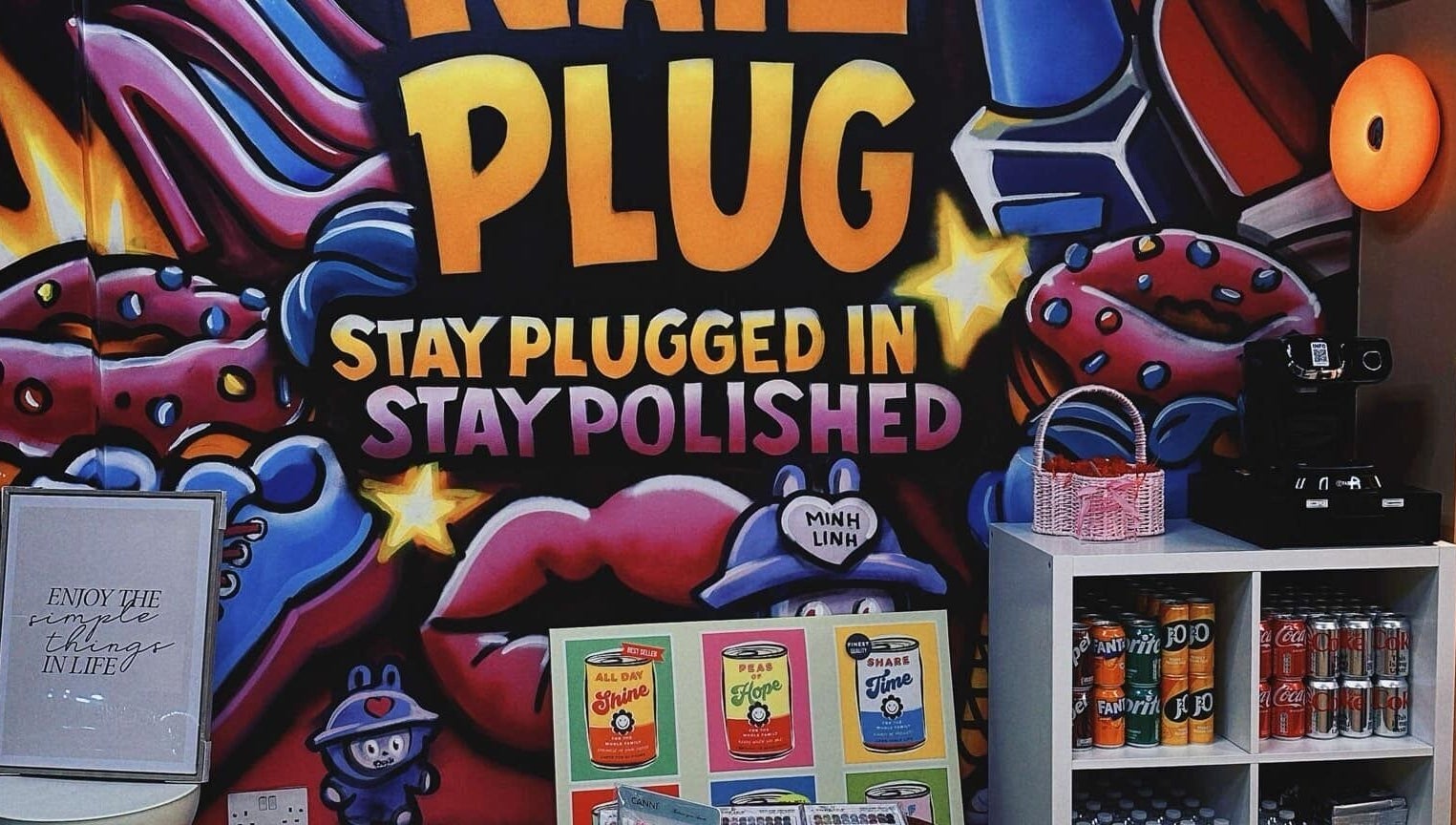 Bright graffiti decor at NailPlug in Urmston, England, GB with colorful designs and beverage display.