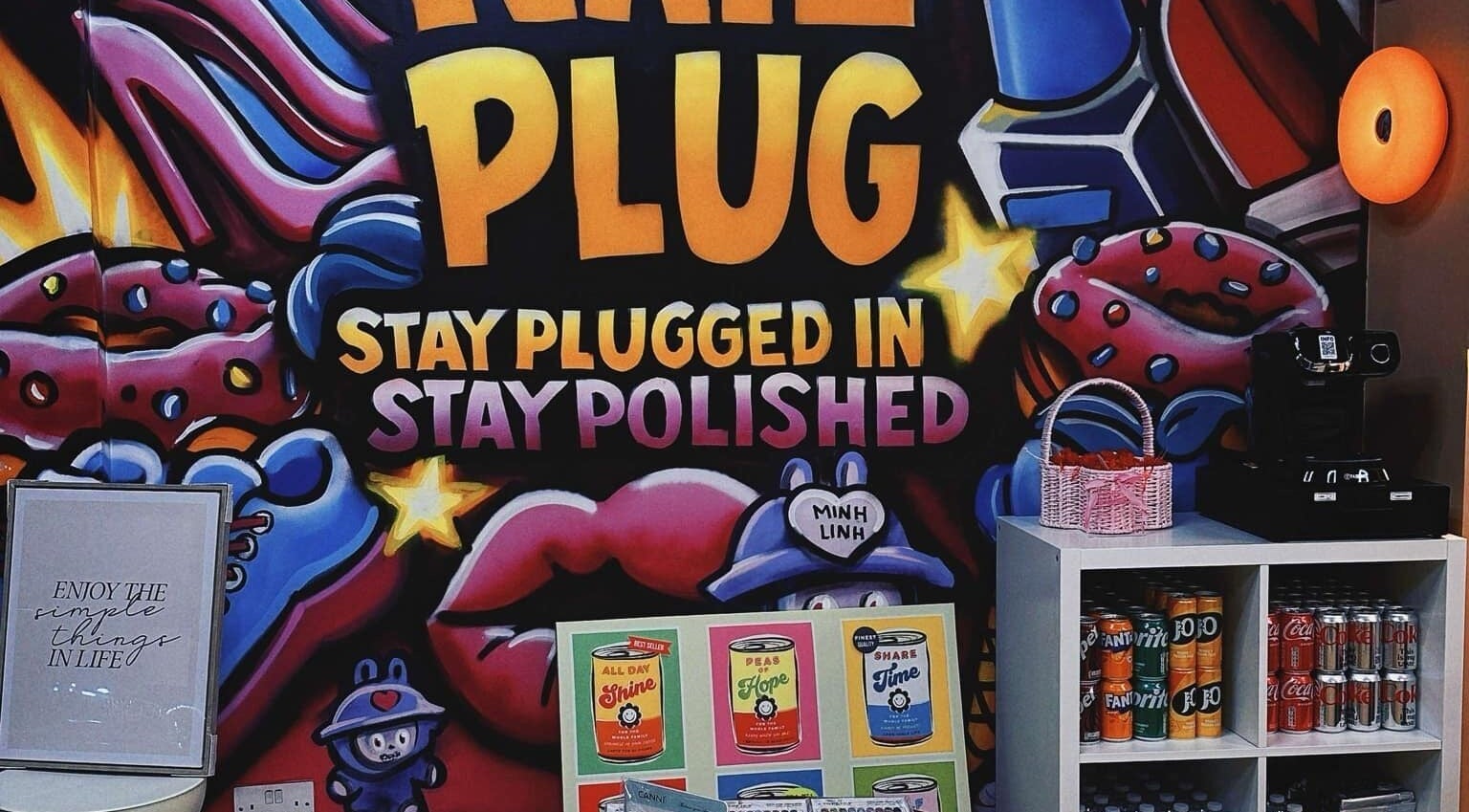 Bright graffiti decor at NailPlug in Urmston, England, GB with colorful designs and beverage display.