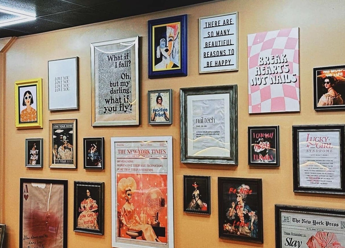 Decorative wall with framed art and quotes at NailPlug in Urmston, England, GB, showcasing stylish ambiance.