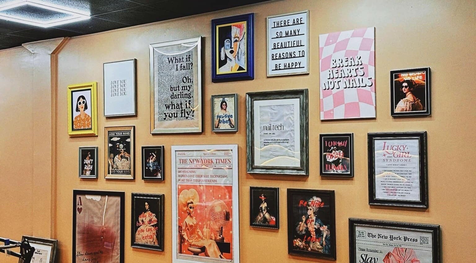 Decorative wall with framed art and quotes at NailPlug in Urmston, England, GB, showcasing stylish ambiance.