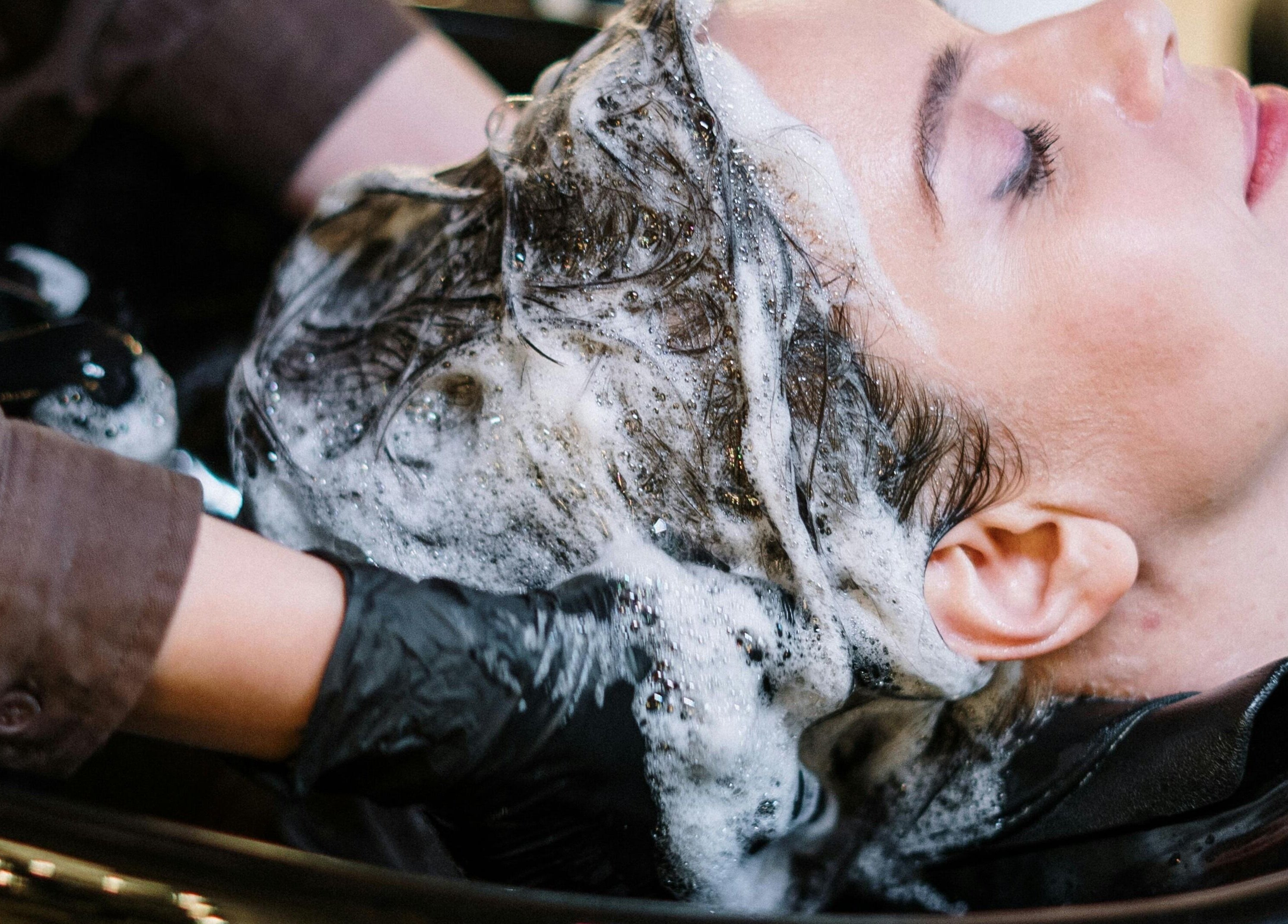 Client détendu recevant un shampooing à Salon Suite 26, Longueuil, Québec, CA. Expérience bien-être et luxe.